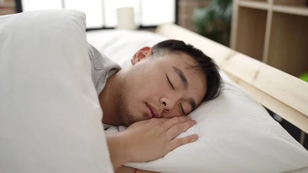 Young chinese man lying on bed sleeping at bedroom